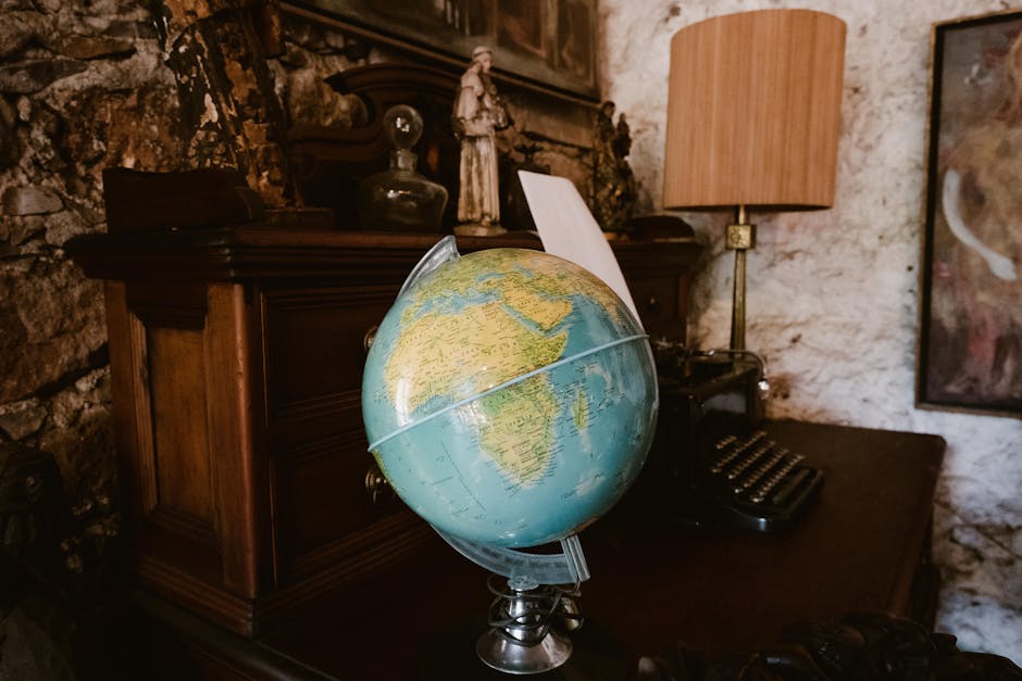 A vintage-style desktop featuring a globe and classic typewriter on a wooden desk.